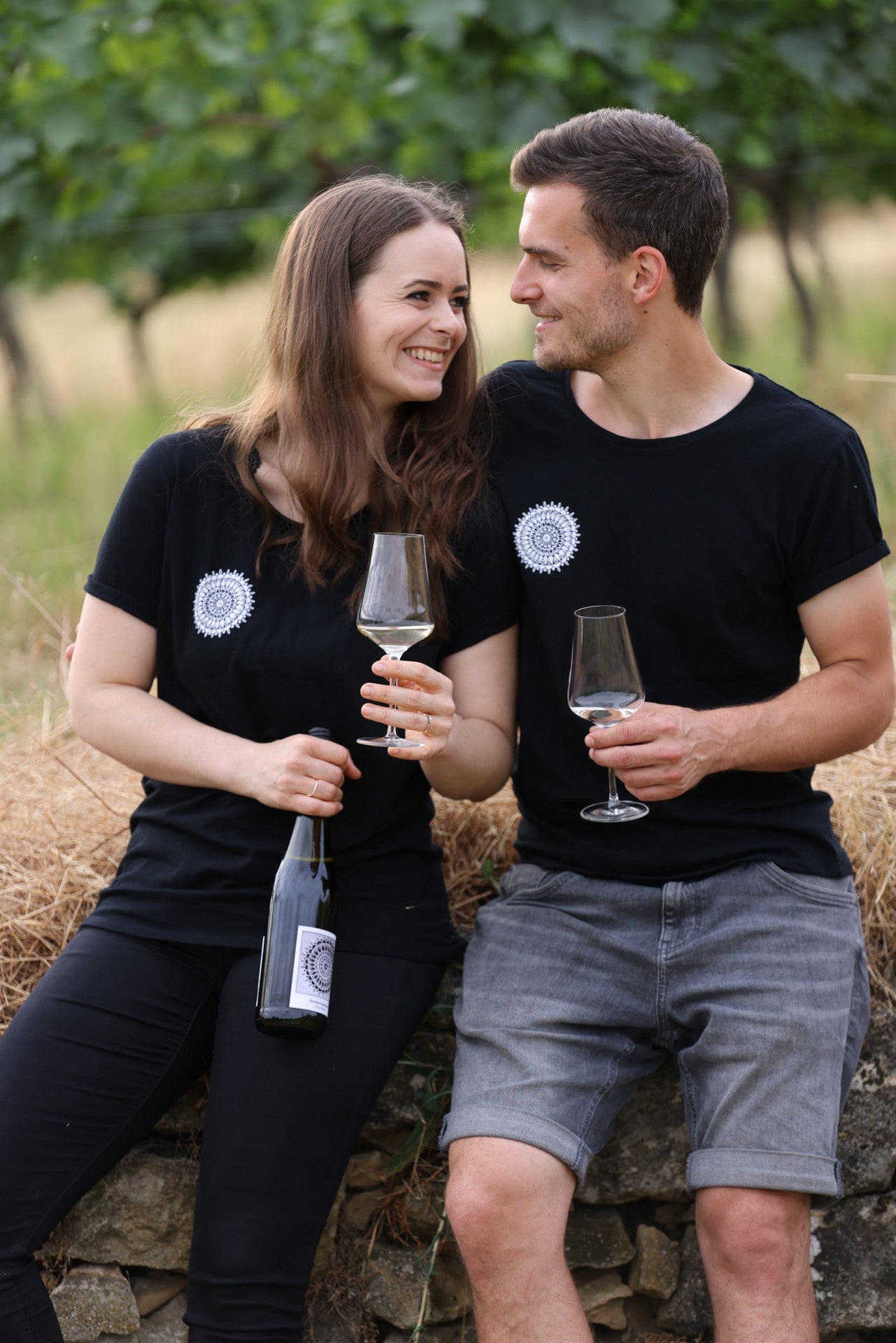 Lena und Sebastian im Weinberg mit Weingläsern und Weinflasche