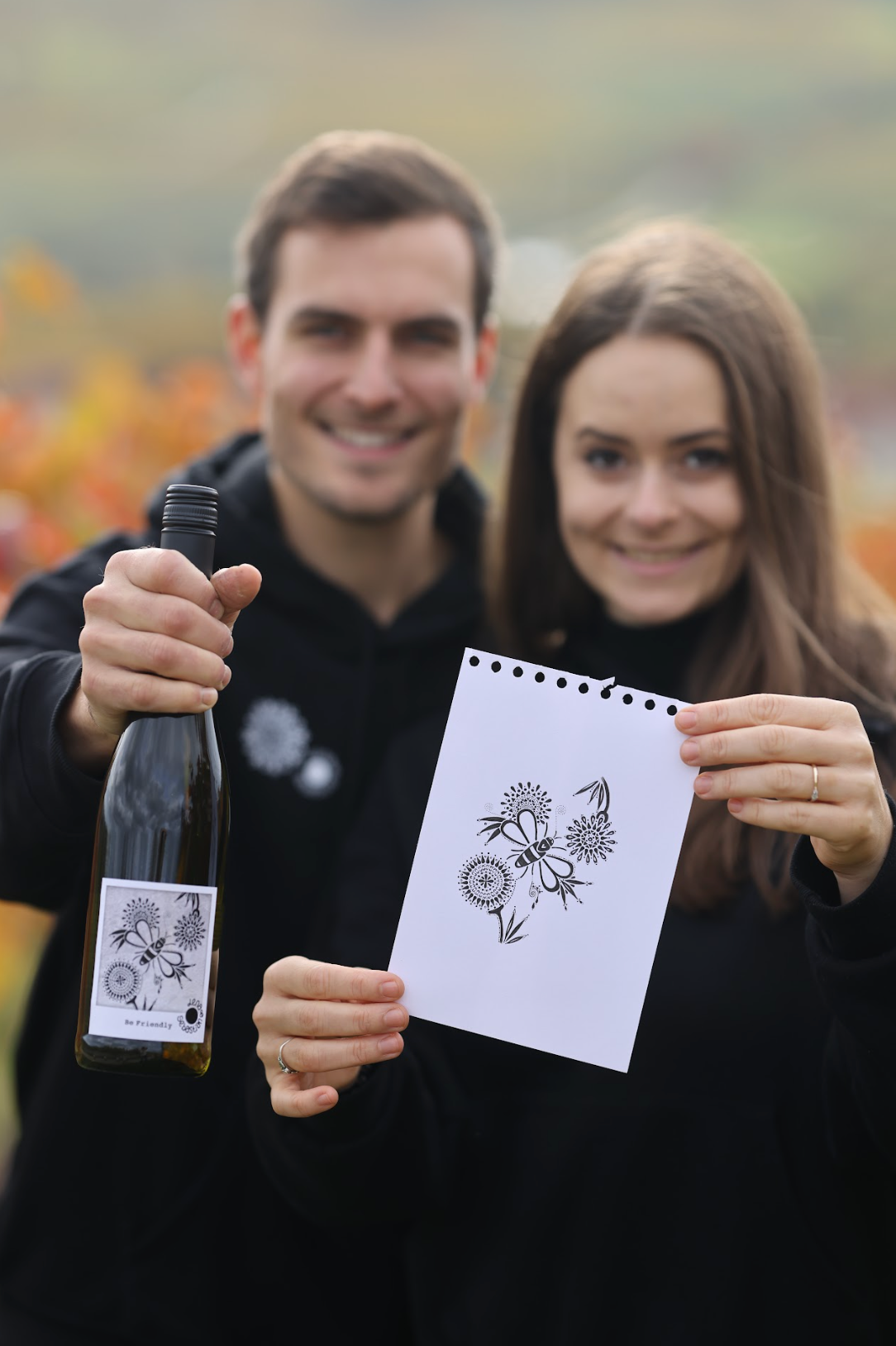 Lena und Sebastian mit handgemalter Skizze von Lena und Weinflasche von Sebastian